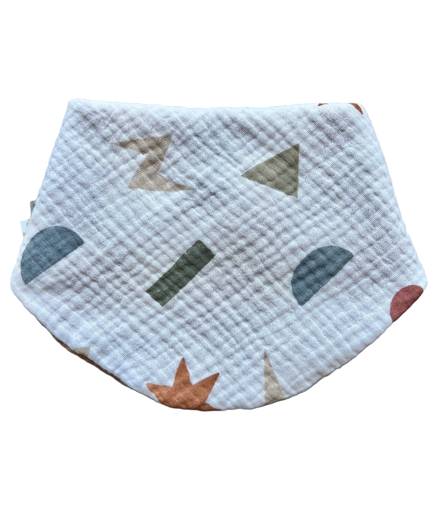 Quilted baby bib with geometric patterns on a light gray background